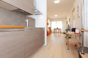 A modern kitchen with a wooden countertop and a built-in stove. There is a dining area with a table and chairs visible in the background. - Lovely three-room apartment located in one of the best areas of Mestre with Fibre Wi-Fi, a lift, a small terrace and a free PRIVATE garage.Located in a modern and quiet context, functionally furnished and equipped with all comforts.The Vespucci stop is (Venezia)