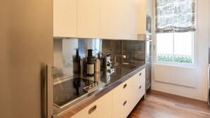 Een moderne keuken met roestvrijstalen apparatuur, witte kasten en een raam met uitzicht op groen.