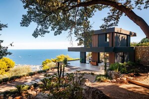 A modern house with a stone wall and a patio overlooking the sea. - Elle Luxury Villa with Pool and Jacuzzi Overlooking Monaco (La Turbie)