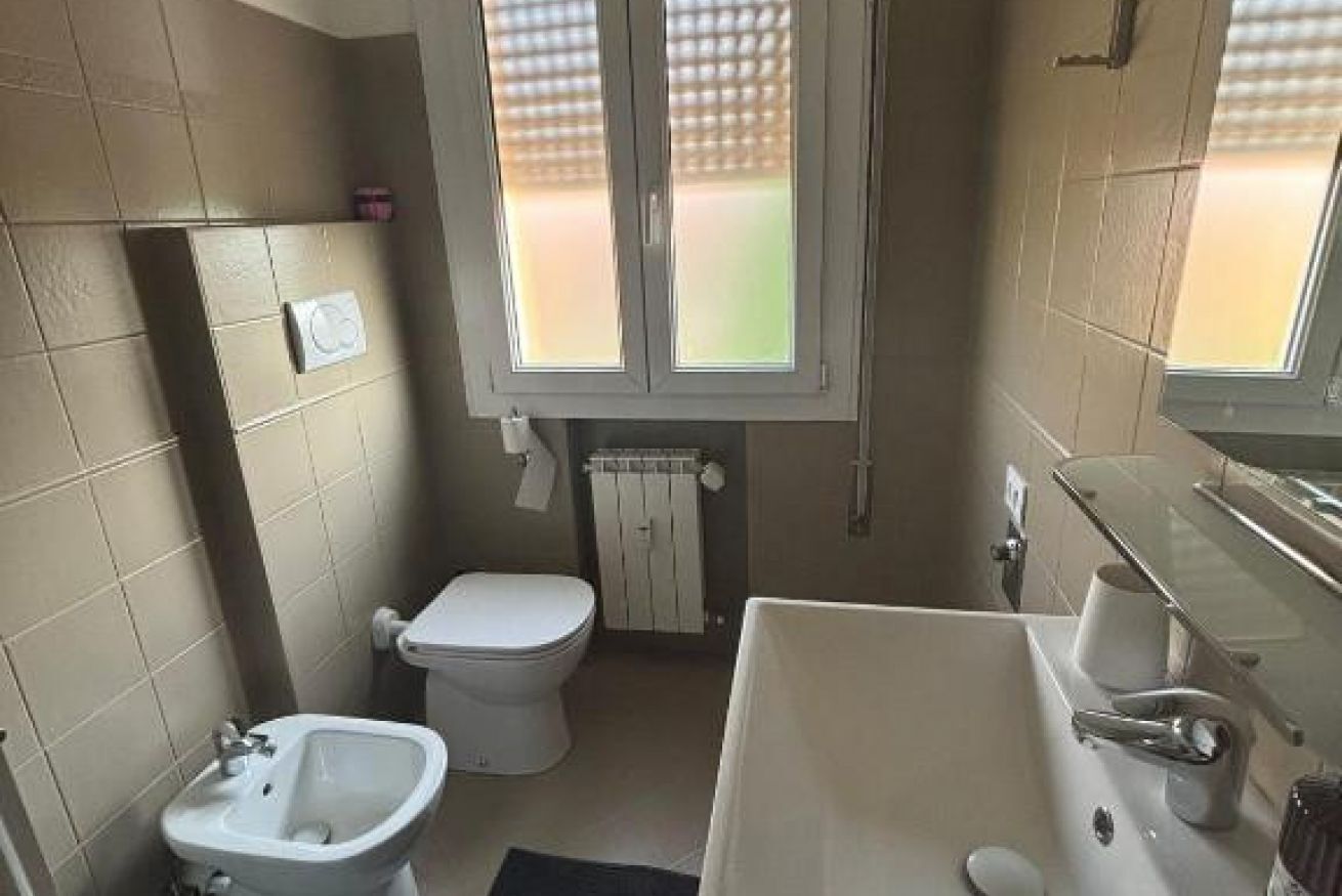 Un bagno compatto con WC, bidet, lavandino e specchio.