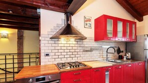 A kitchen with red cabinets, a gas stove, a stainless steel sink, and a brick wall backsplash. - The SpaceDreaming of a stay filled with history, charm, and comfort just a few kilometers from Venice and the Venetian Villas?This beautiful two-story independent house, with its mix of rustic and modern style, is the perfect retreat for those seeking bo (Mira)