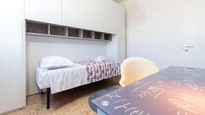 A small room with a bed, a desk, and a chair. There is a shelf above the bed and a door on the right. - The SpaceLooking for a comfortable, stylish, and strategically located stay to explore Venice and beyond? This newly renovated home in Mestre is the ideal solution for families, small groups, and travelers seeking both comfort and convenience.Just steps  (Venezia)