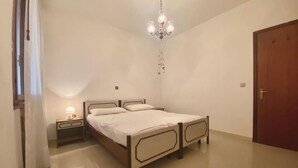 A bedroom with a bed, nightstand, and a chandelier. - Sottomarina - House Near Sea | Terrace & Private Garage (Chioggia)