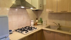 A kitchen with a gas stove, a sink, and wooden cabinets. - Sottomarina - House Near Sea | Terrace & Private Garage (Chioggia)