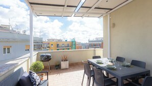 Un balcon avec une table dressée pour les repas, un barbecue et des plantes en pot.