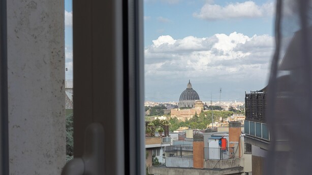 Une vue sur un paysage urbain à travers une fenêtre, avec notamment un imposant dôme et les bâtiments environnants.