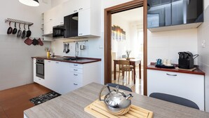 Une cuisine moderne avec des meubles blancs, un four à micro-ondes et une bouilloire posés sur le plan de travail.