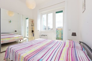 A bedroom with two beds, a large mirror, a window, and a bookshelf. - Rental in Rome Saint Peter View Penthouse (Rome)