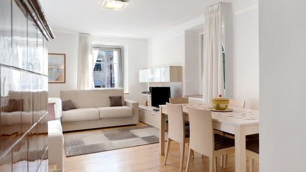Un salon moderne avec un canapé, un téléviseur, une table à manger et une vue sur la ville.