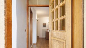 Un couloir avec une porte en bois, un radiateur et un petit meuble.