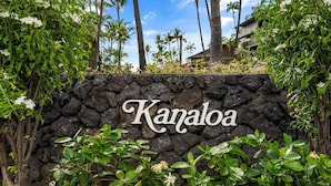 A stone wall with the name 'Kanaloa' and tropical vegetation around it. - Large 3BR + Loft at Kanaloa Pools, Golf Views & Prime Keauhou Location (Kailua-Kona)
