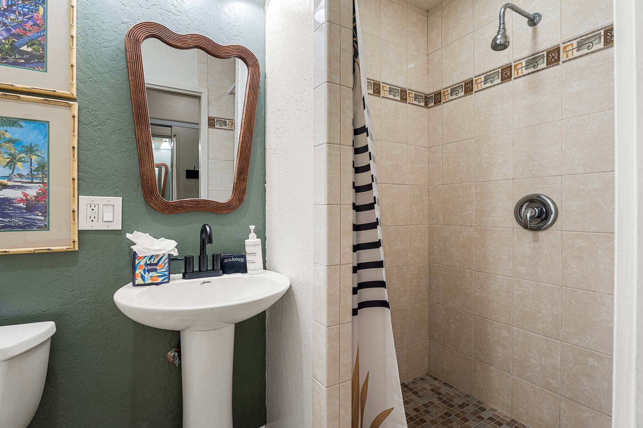 A bathroom with a sink, mirror, shower, and decorative tiles.
