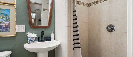 A bathroom with a sink, mirror, shower, and decorative tiles.