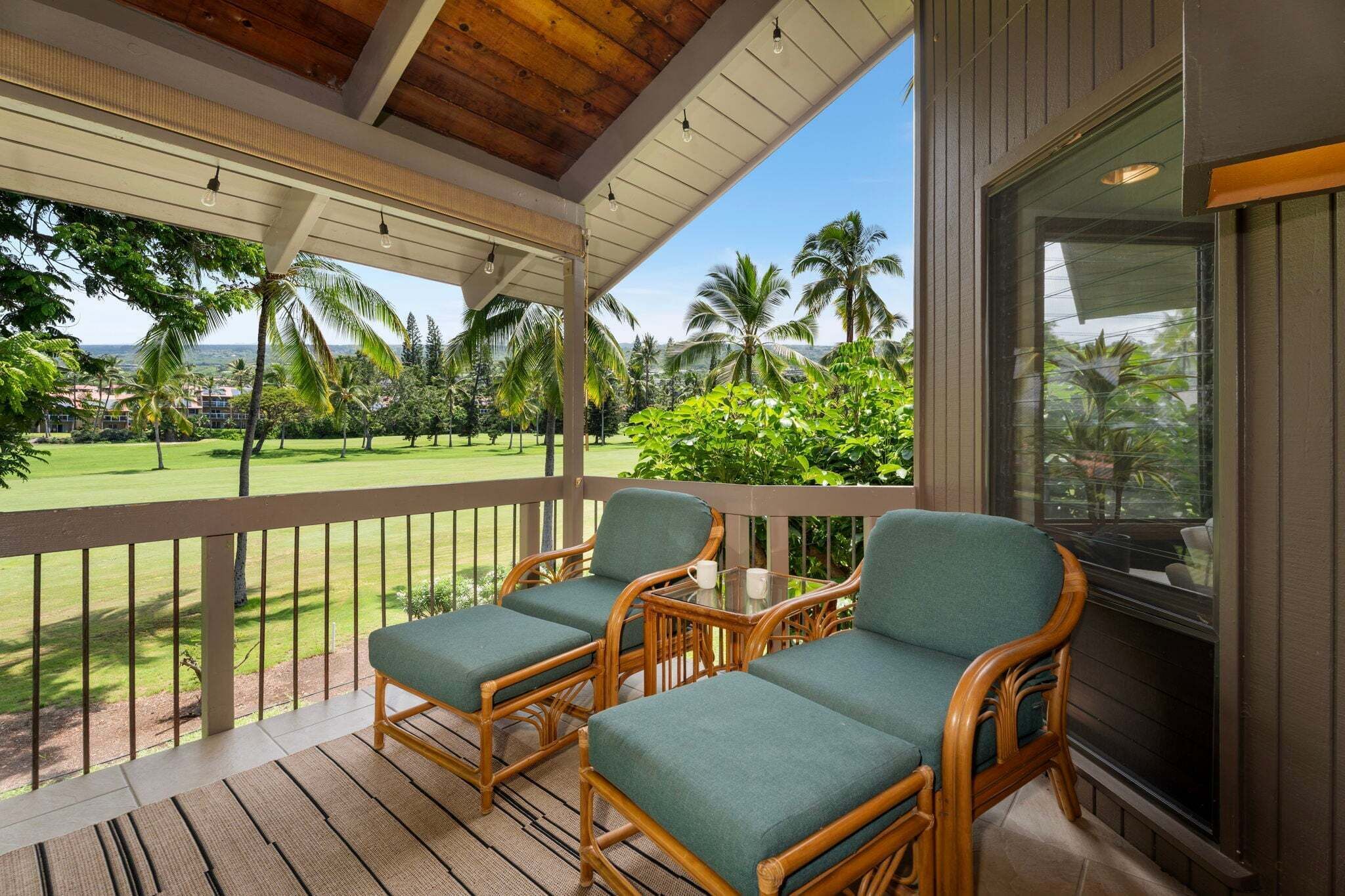 A covered outdoor area with wicker furniture and a view of a golf course.