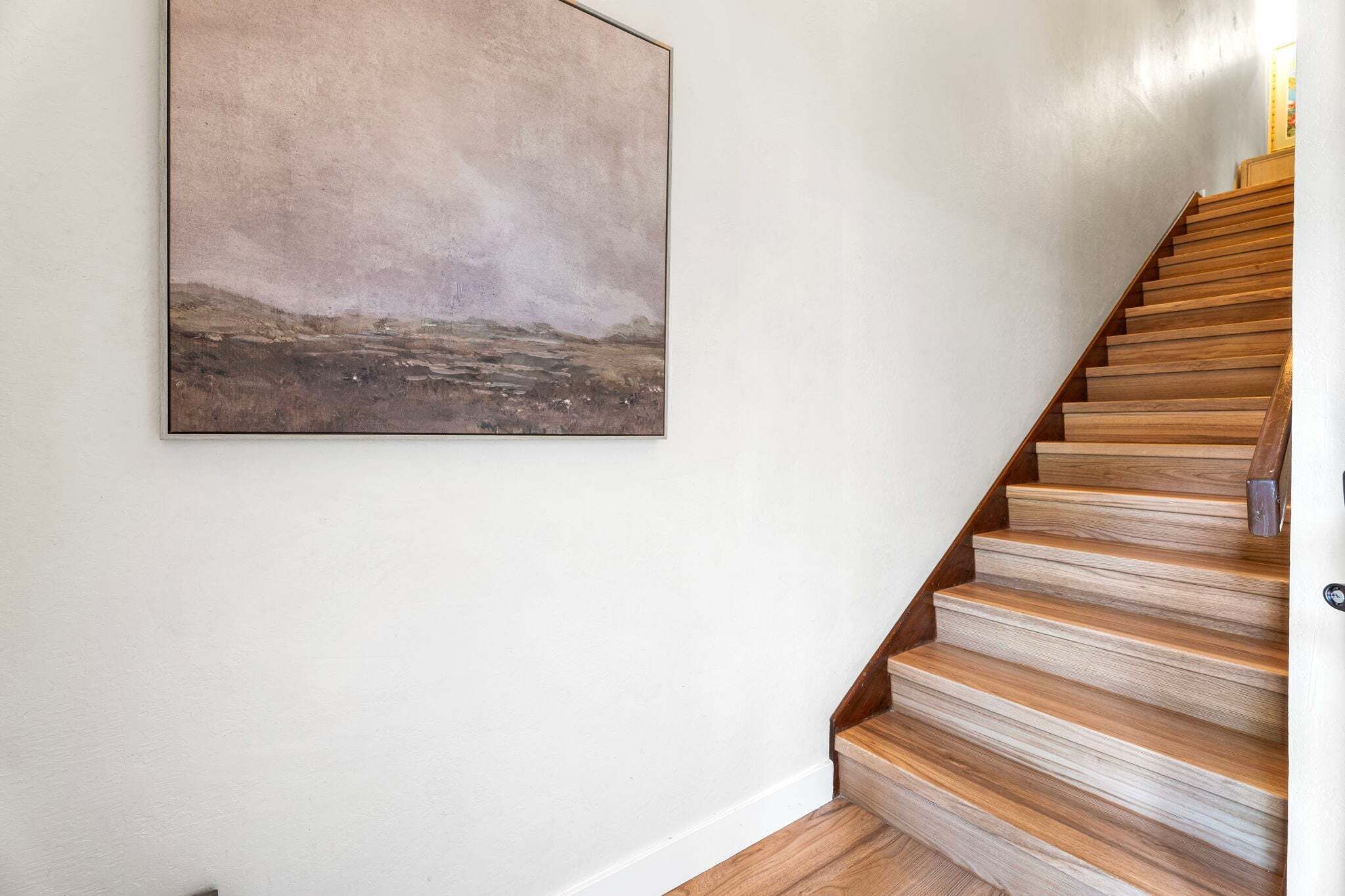 Un escalier avec des marches en bois et un tableau accroché au mur.