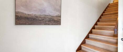 Un escalier avec des marches en bois et un tableau accroché au mur.