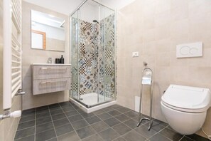 Ein modernes Badezimmer mit Duschkabine, Toilette, Waschbecken mit Spiegel und Fliesenboden.