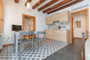 A compact kitchen with a dining area, featuring wooden beams, a tiled backsplash, and a small dining table with chairs. - The Space🌉 Rialto 1 – Elegant Apartment in the Heart of Venice!Welcome to your corner of authentic Venetian living, a spacious and refined apartment located in the heart of Venice, just steps from the famous Rialto Bridge and the historic fish marke (Venezia)