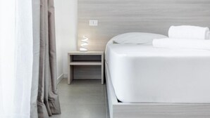 A modern bedroom with a wooden headboard, a bedside table with a lamp, and a neatly made bed. - 🏡 Modern & Functional Rooms in Mestre – Brand-New Guesthouse with Free ParkingPerfectly located for Venice: bus no. 5 passes every 10 minutes and takes you directly to the historic center in just a few minutes! Rooms are equipped with a comfortable  (Venezia)