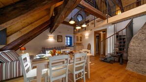 Een loft-achtige kamer met een eethoek, een trap en een keuken.