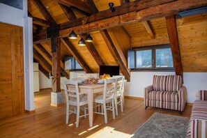 A dining area with a wooden table and chairs, a striped sofa, and a window with a view.