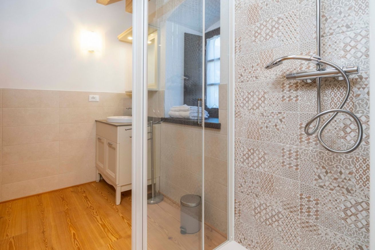 Un baño con ducha, puerta de cristal, lavabo e inodoro.