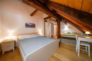 A bedroom with a wooden ceiling, a bed, a desk, and a chair.
