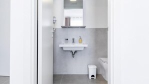Un baño moderno con un lavamanos blanco, un espejo y un inodoro.