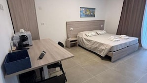 A hotel room with a bed, a desk, a chair, a nightstand, and a painting on the wall. - 🏡 Modern & Functional Rooms in Mestre – Brand-New Guesthouse with Free ParkingPerfectly located for Venice: bus no. 5 passes every 10 minutes and takes you directly to the historic center in just a few minutes! Rooms are equipped with a comfortable  (Venezia)