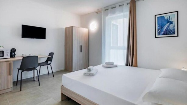 A modern hotel room with a bed, a desk, a chair, a wardrobe, a flat-screen TV, and a window with curtains. - 🏡 Modern & Functional Rooms in Mestre – Brand-New Guesthouse with Free ParkingPerfectly located for Venice: bus no. 5 passes every 10 minutes and takes you directly to the historic center in just a few minutes! Rooms are equipped with a comfortable  (Venezia)