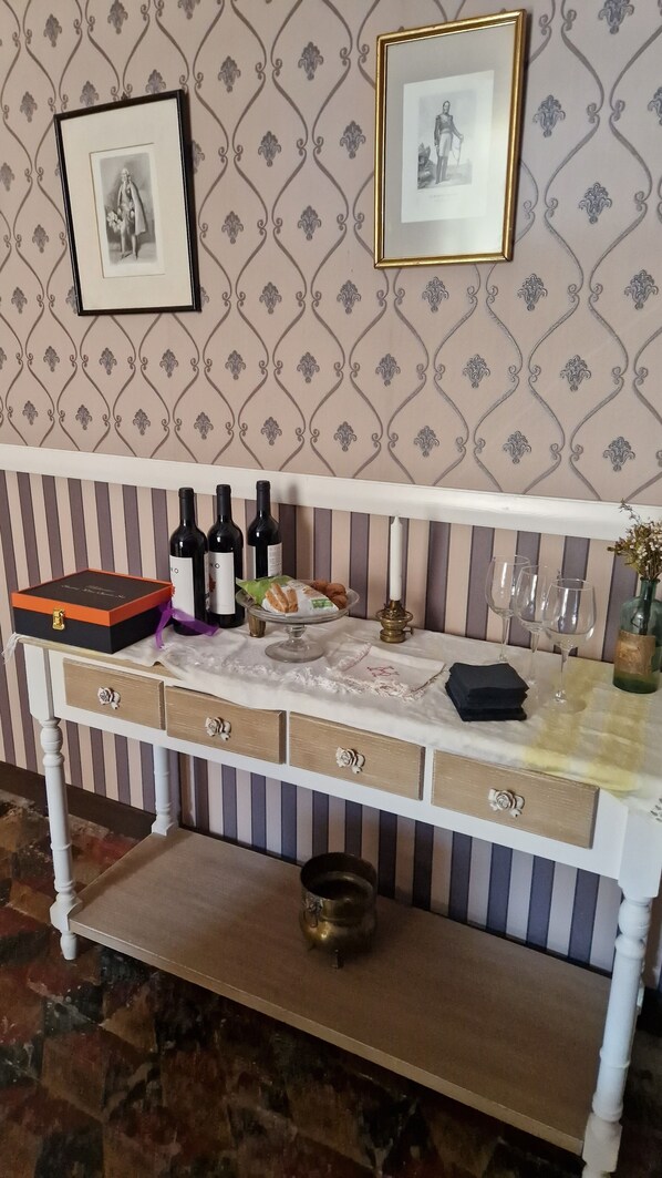 A bar area with a white bar counter, wine bottles, glasses, and a candle. - Casa palaciega Doña Leocadia (Viana)