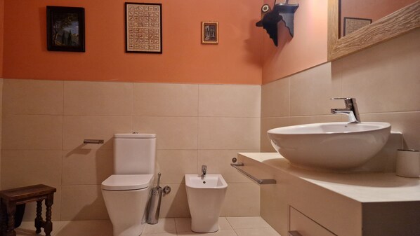 Un baño con inodoro, bidé, lavamanos y espejo.
