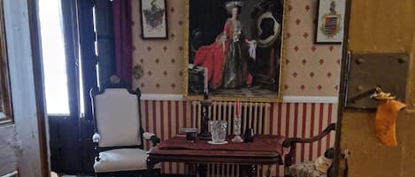 Une pièce avec un sol à carreaux, un lustre, un tableau et un canapé rayé de rouge et de blanc.