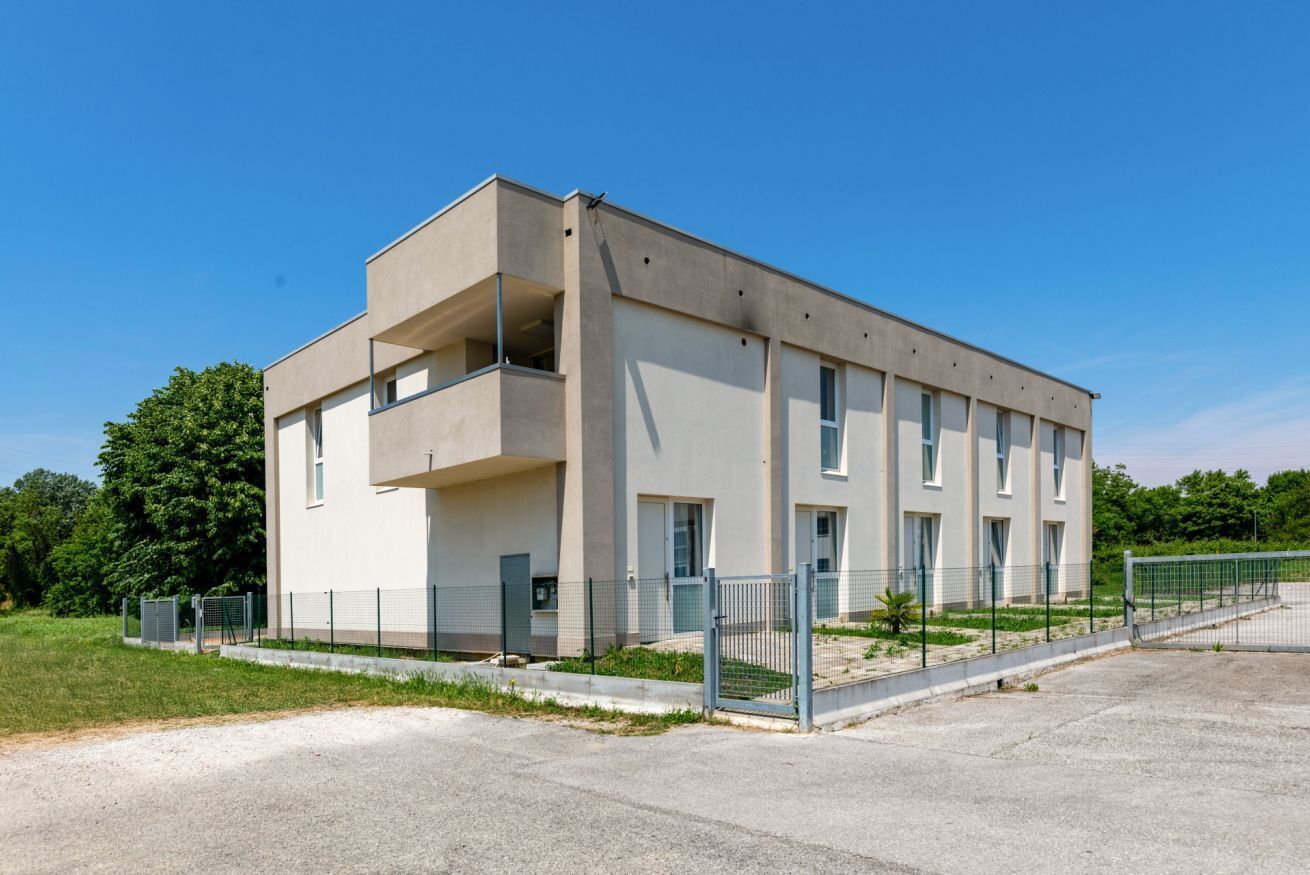 Un bâtiment moderne doté d’un toit plat, de grandes fenêtres et d’un balcon situé sur le côté gauche.