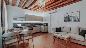 Una sala moderna con techo de madera, un comedor con sillas y mesa, una cocina con armarios y encimera, y un sofá con mesita de centro.