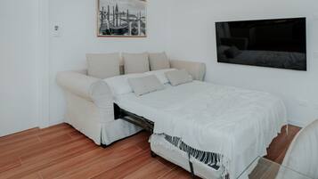 Un dormitorio con una cama, un sofá, un televisor y un cuadro en la pared.