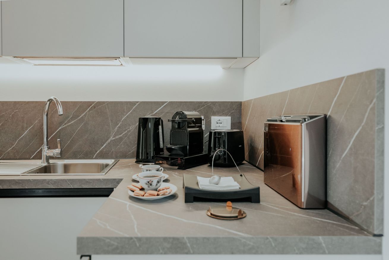 Una cocina moderna con un lavamanos, cafetera, tostadora y un pequeño espacio para el desayuno.