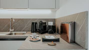 Una cocina moderna con un lavamanos, cafetera, tostadora y un pequeño espacio para el desayuno.