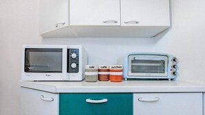 Eine Küchenzeile mit einer Mikrowelle, einem Toaster und Gläsern, die mit 'Sale', 'Caffè' und 'Zucchero' beschriftet sind.