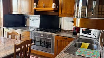 Uma cozinha com armários de madeira, fogão, forno, micro-ondas e pia.