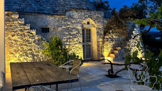 A stone building with conical roofs, a wooden table, and metal chairs in a garden setting. - The Space🌿 Trullo Scirocco – Sleep Under Puglia’s Stars, Live the Magic of the Trulli ✨Wake up to birdsong, breathe in the scent of centuries-old olive trees, and walk barefoot on warm stone. Welcome to Trullo Scirocco, a one-of-a-kind home in t (Ostuni)