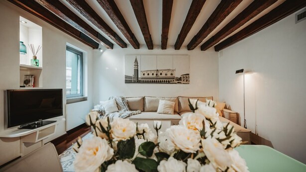 Quarto com cama, televisão, janela e pintura de um edifício.