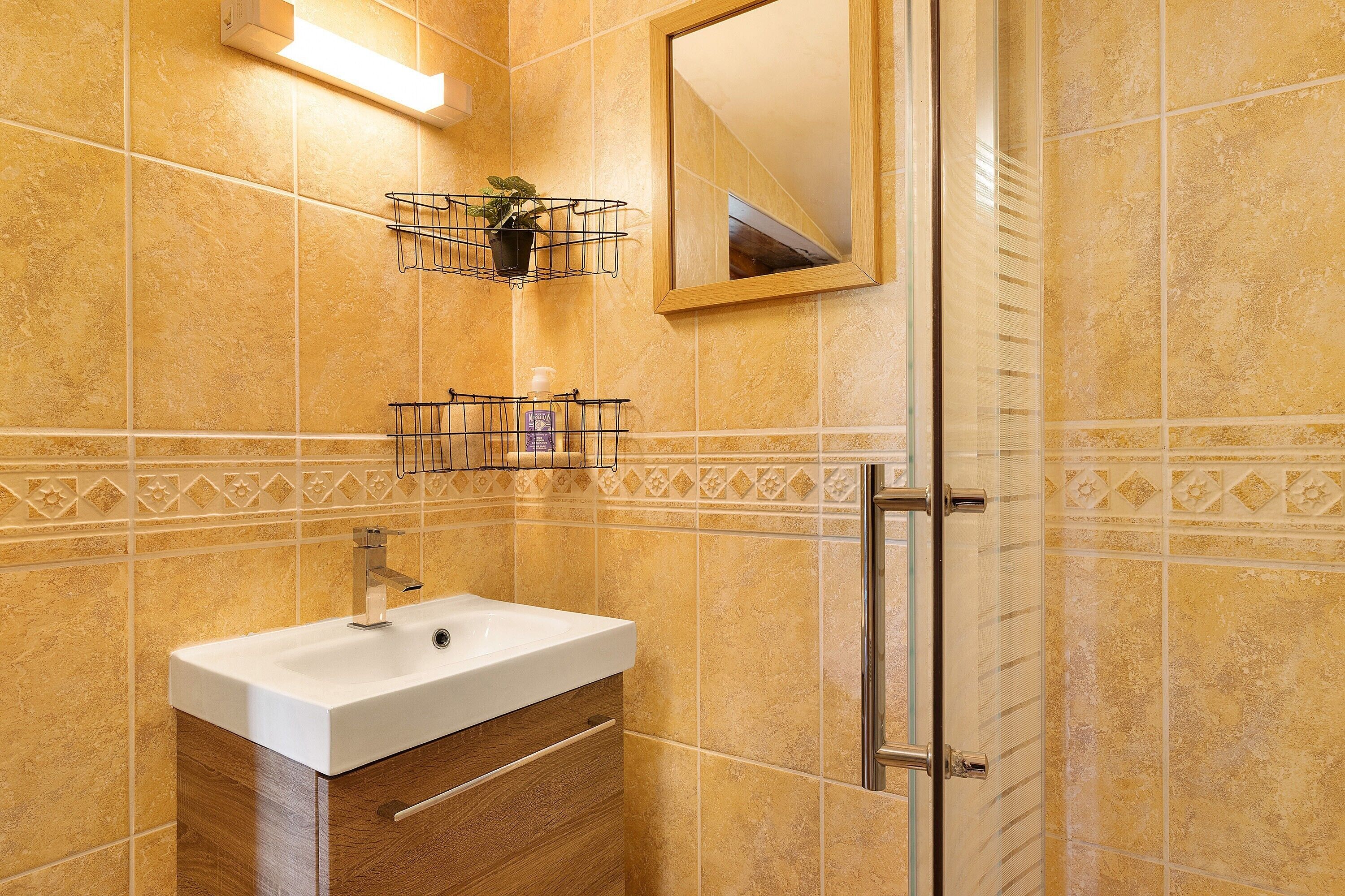 A bathroom with a white sink, wooden cabinet, and a mirror.