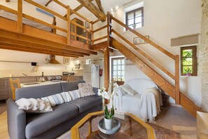 A spacious living area with a sofa, a coffee table, and a staircase. - Gîte des Fraignaies with Private Pool and Terrace in Saint-Juire-Champgillon (Saint-Juire-Champgillon)