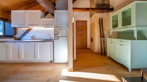 Een keuken met witte kasten, een koelkast en een houten plafond.