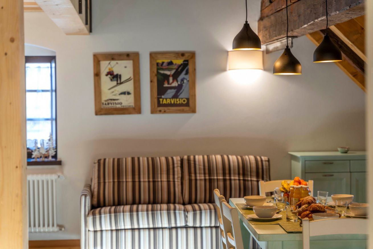 Una stanza accogliente con un divano a righe, un tavolo da pranzo con colazione servita e due poster incorniciati appesi al muro.