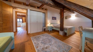 Een slaapkamer in loftstijl met zichtbare houten balken, een bed, een bureau en een stoel.
