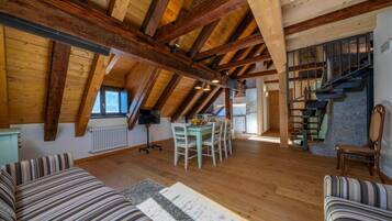 Un loft spazioso con travi a vista in legno, una zona pranzo, una scala e un'accogliente area salotto.
