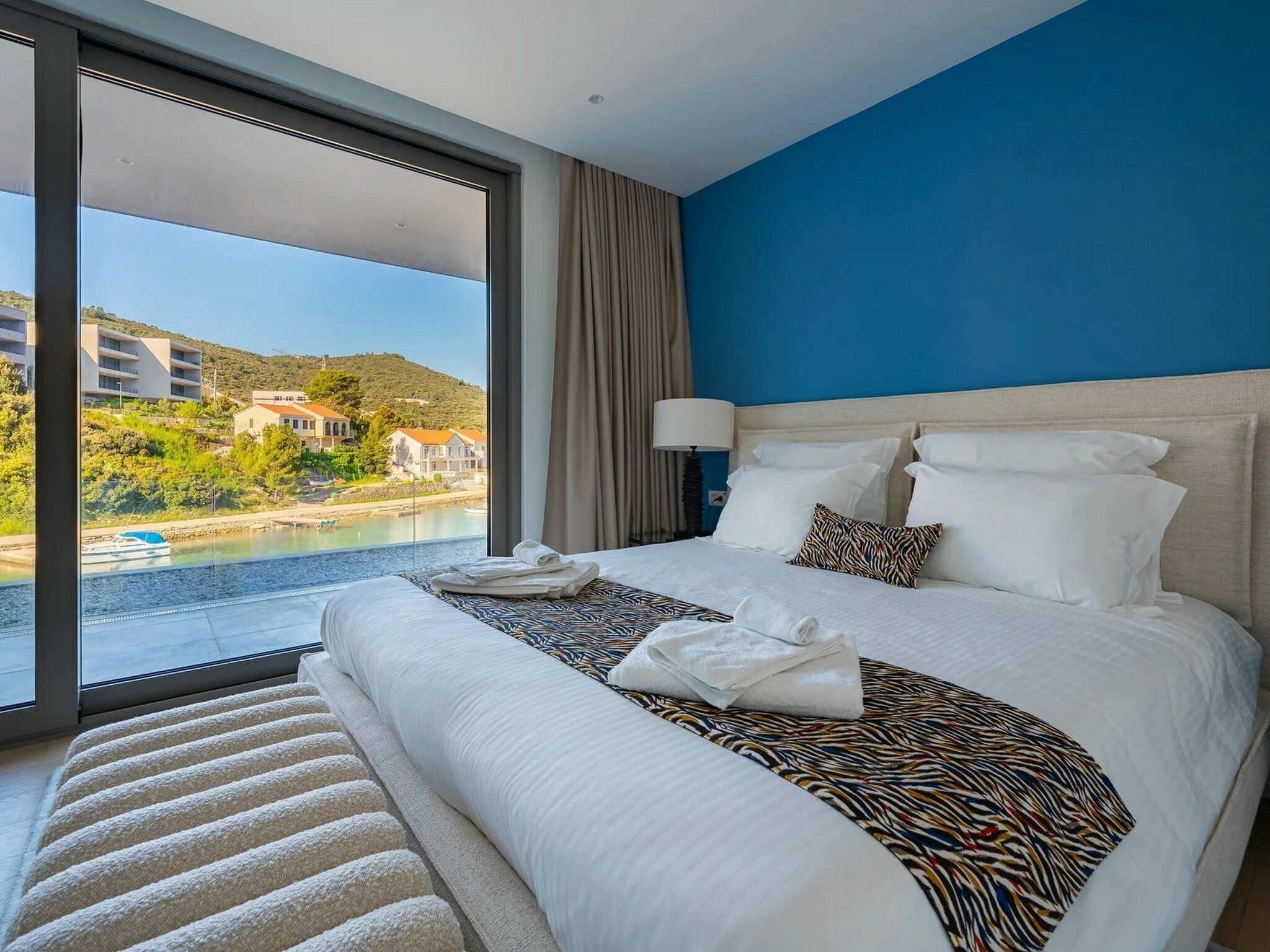 A hotel room with a large bed, a view of a body of water, and a balcony.