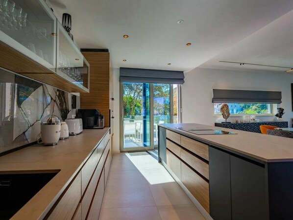 A modern kitchen with a large island, built-in appliances, and a view to the outdoors.